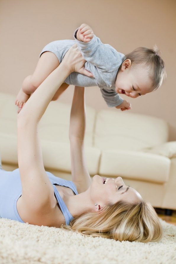 Mother laying on floor playing with her baby باروری با طب سوزنی و ART