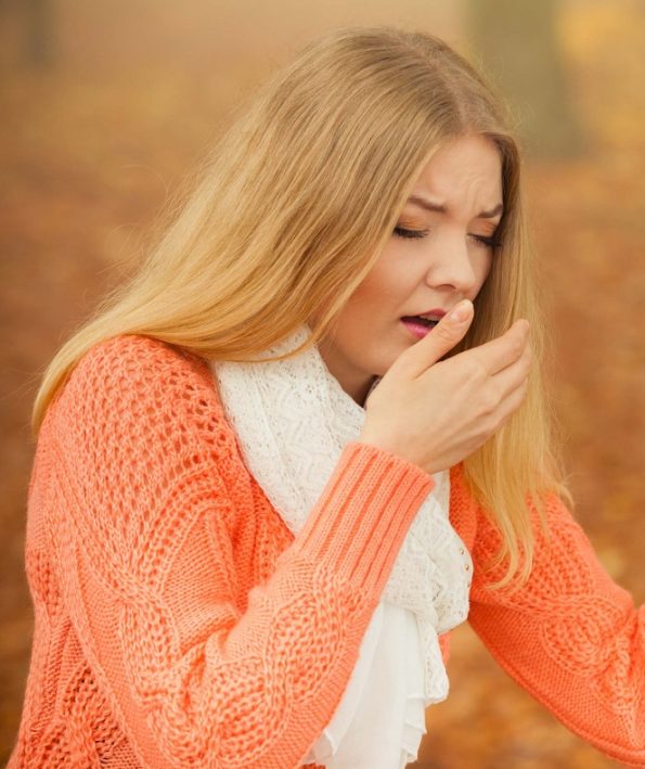 Sick ill woman in autumn park sneezing in tissue. آلرژی در فصل پاییز